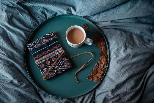 Jahresrückblick - Notebook und Kaffeetasse auf dunkelgrünem Tablett auf dunkelgrüner Bettdecke