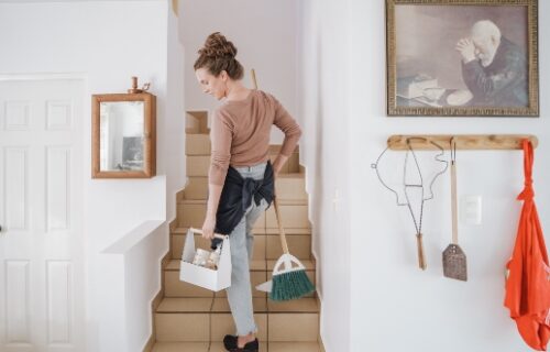 Frau mit Reinigungsequipment auf der Treppe