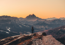 Frau steht im Gebirge und blickt dem Sonnenuntergang entgegen - Zeit für Reflexion und Bewusstsein